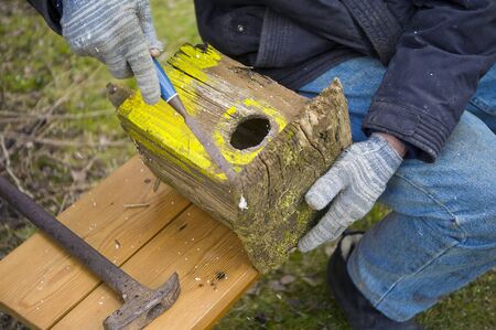 A man sitting on a bench and fixing old birdhouse