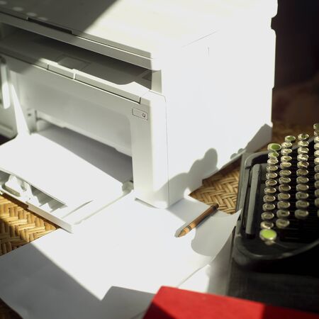 Retro typewriter and a modern printer placed on a table