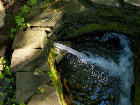 artificial waterfall filling a pond, outdoor summertime  shot