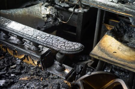 Burnt wooden armchair in a room destroyed by fire, indoor closeup