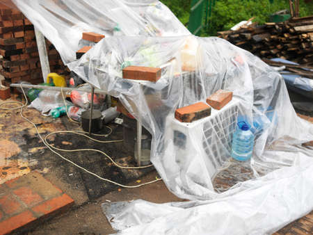 Cellophane foil covering household stuff abandoned under rain, outdoor closeup