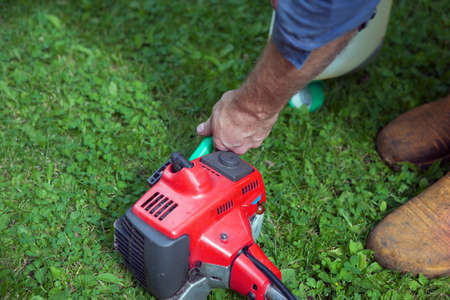 A woreker carefully pouring petrol into a chainsaw, outdoor shot