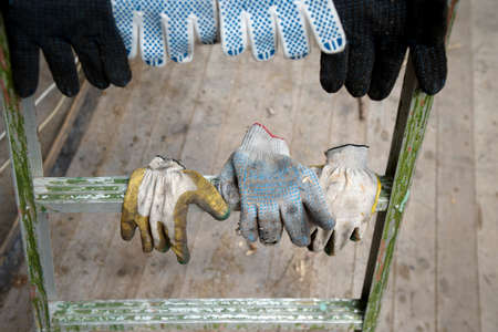 Worker textile used gloves hanging on a ladder, outdoor shotの写真素材