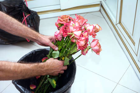 male hands throwing a rose bouquet into a garbage bin, concept of end of love, shallow DOFの写真素材