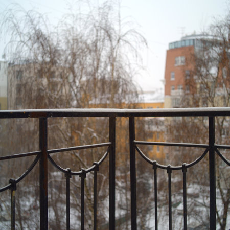 Snow on a balcony handrails, an urban landscape in the blurred backgroundの写真素材