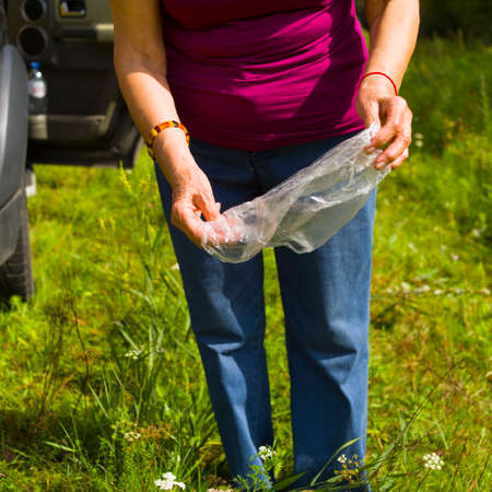 A woman about to throw away cellophane bag, summertime shot