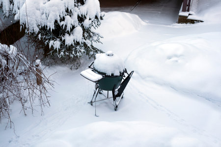 Portable grill abandoned in the snowy yard, winter sceneの写真素材