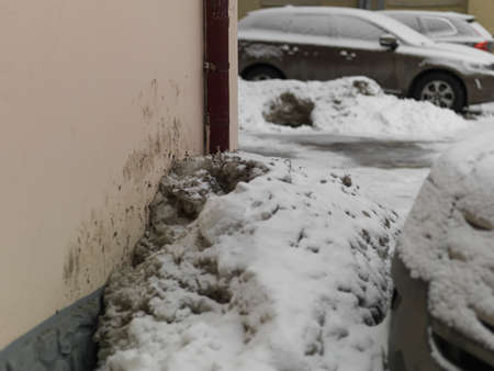 Downspout and a pile of dirty snow, urban sceneの写真素材