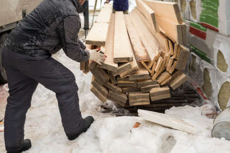 Workers offloading sawn timber on the snow, winter sceneの写真素材