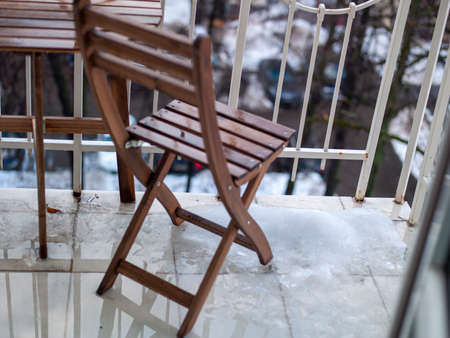 Wooden furniture and melting snow on a balcony, daylight outdoor shotの写真素材