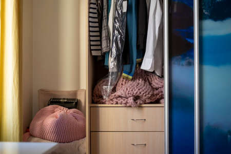 Open door of a wardrobe with hanging clothes, indoor cropped shotの写真素材