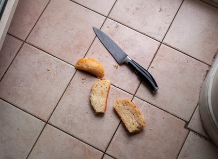 Slices of bread and kitchen knife abandoned on the tiled floorの写真素材