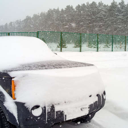 Front of a car, covered with snow and ice, winter outdoor shot, square composition
