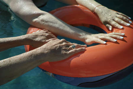 Two women holding a swimming ring in a pool, outdoor shot with no people