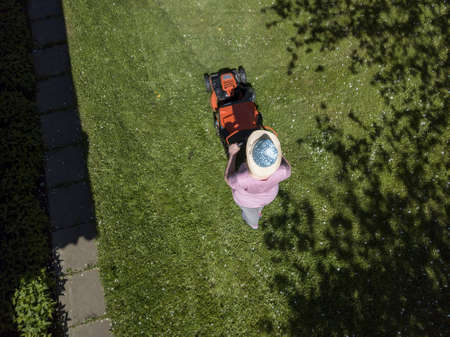 Overehad view of a woman pushing lawnmower, summertime photo
