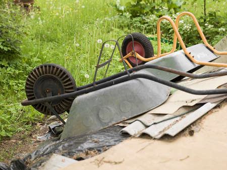 Two turned over garden trolleys next to a pile of household trashの写真素材
