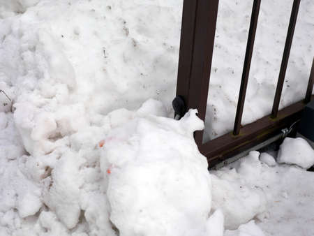 Electric sliding gate stuck in the snow pile, outdoor closeup