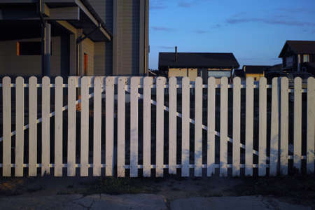 a timber fence in the foreground and estate in the background, twilight sceneの写真素材
