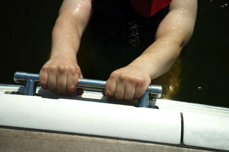 hands gripping a handle while a man climbing out of waterの写真素材