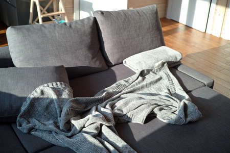 a room full of morning light and unmade sofa with crumpled plaidの写真素材