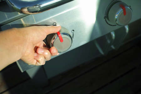 Closeup of a hand adjusting heat on a grill or stove, outdoor shot