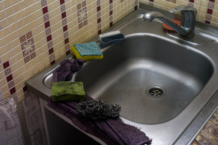 Dirty sponge and rag around a kitchen sink, indoor close upの写真素材