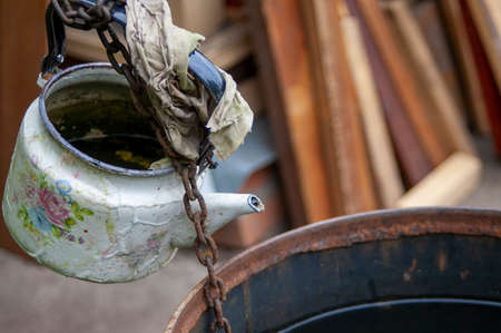 old kettle hanging on a chain above a water barrelの写真素材