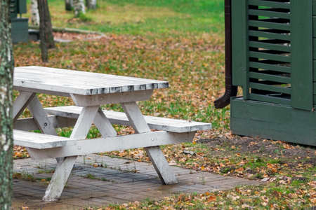 a wooden table and bench painted in white outside a house