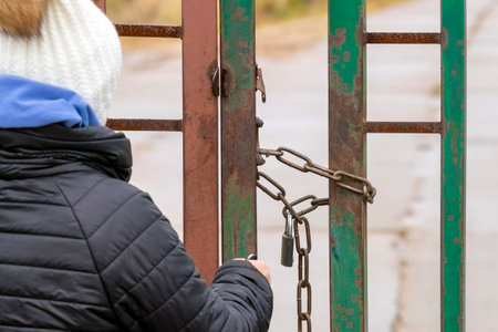 a woman locking a metal door with huge steel chain, outdoor shotの写真素材