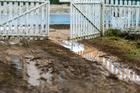 messy road and half open wooden gate, autumn daylight shotの写真素材