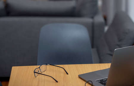extremely shallow DOF shot of a laptop and spectacles abandoned on a tableの写真素材