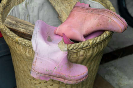 Torn pink rubber boots abandoned in a rubbish bin