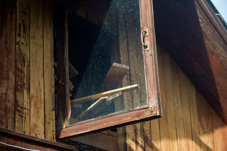 Open window of wooden house attic used as a storage for boardsの写真素材