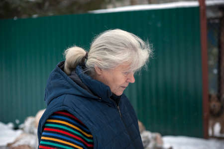 retired woman walking with bare gray head, winter scene