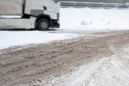 dirty sludgy road and truck in the blurred background, winter sceneの写真素材