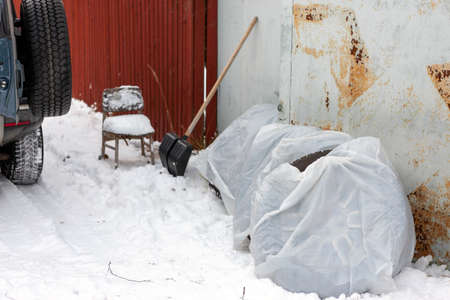 a garage door blocked with snow and winter tires in plastic bagsの写真素材