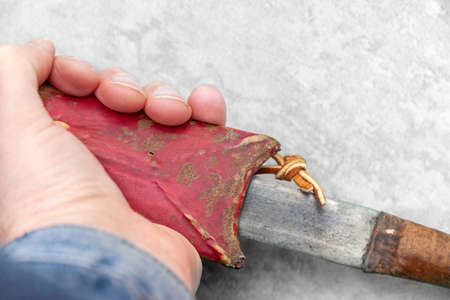Old red leather sheath and vintage knife in a male hand, studio closeup