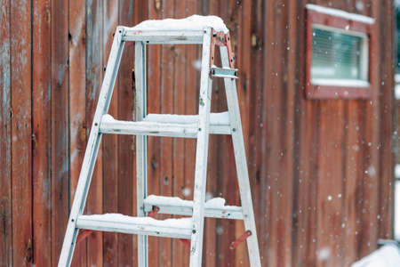 aluminum stepladder abandoned outdoor under snowfall, winter sceneの写真素材
