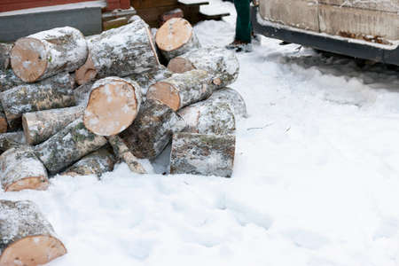 A pile of cut birch tree offloaded on the snow and minivan in the background, winter sceneryの写真素材