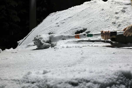 a snow brush abandoned on a car hood, night sceneの写真素材