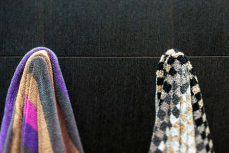 shallow dof shot of two colorful bath towels hanging on the wall of bathroom, tilt shift close upの写真素材