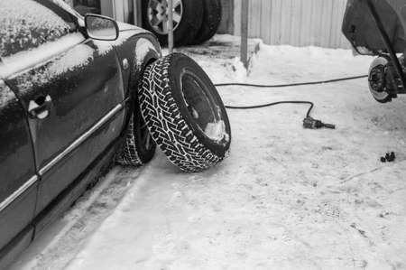 car lifted up with car jack for urgent outdoor wheels replacement, winter scene in black and white