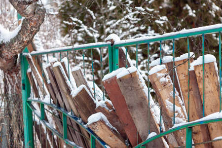 stack of old rustic boards leanaed against the fence, winter sceneの写真素材