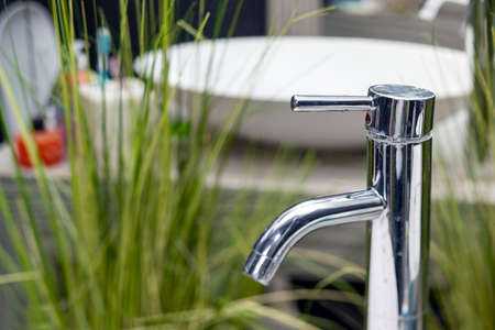 a bath tap and artificial plants in the blurred background, indoor closeupの写真素材