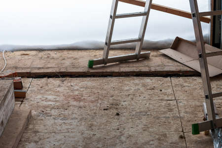 expandable aluminum ladder on the dirty floor of unfinished building