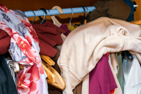an open wardrobe with collection of clothing in mess, indoor closeup