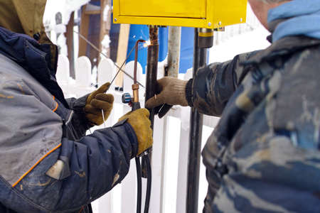 two welders busy with LPG pipeline maintenance, outdoor winter sceneの写真素材