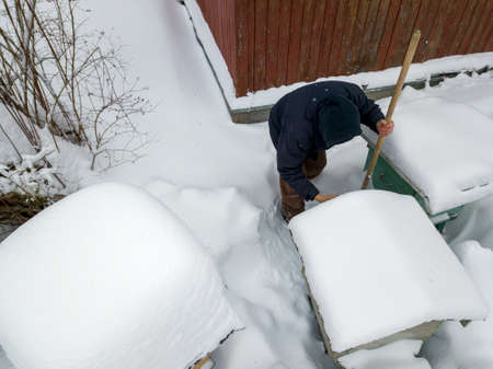 a beekeeper with shovel in hand inspecting a hive, winter scene