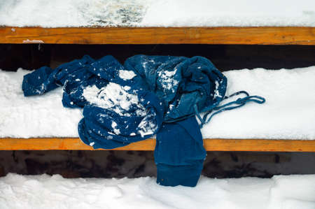 blue sweatshirt abandoned on the wooden steps covered with snow