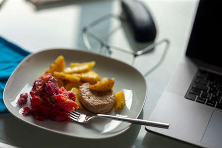 a plate with lunch next to a laptop on a table, shallow dofの写真素材